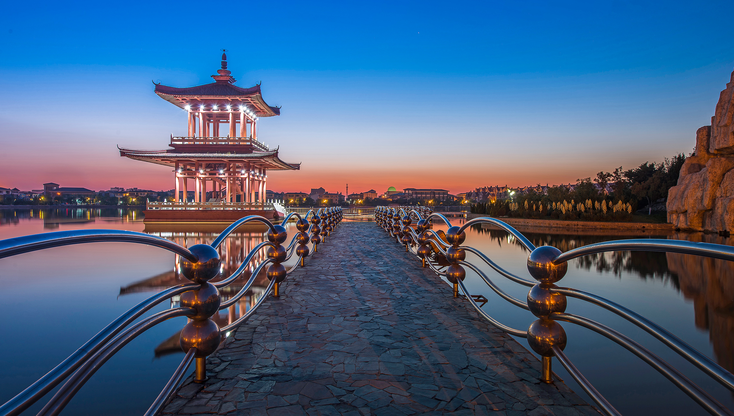 A traditional Chinese pavilion on a serene lake at sunset \| MSC Cruises