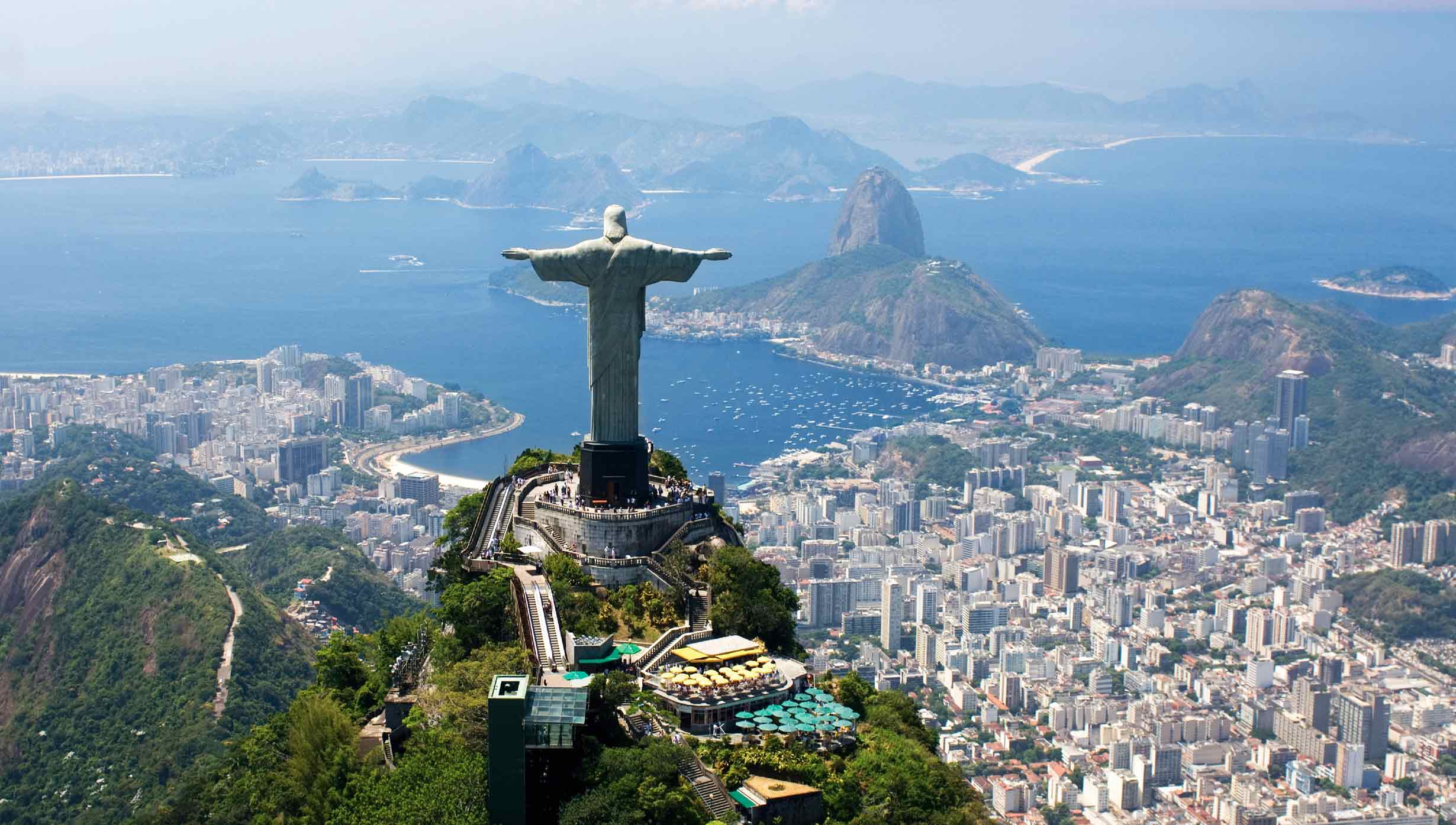 Christ the Redeemer overlooking Rio de Janeiro with Sugarloaf Mountain and the bay in the background \| MSC Cruises