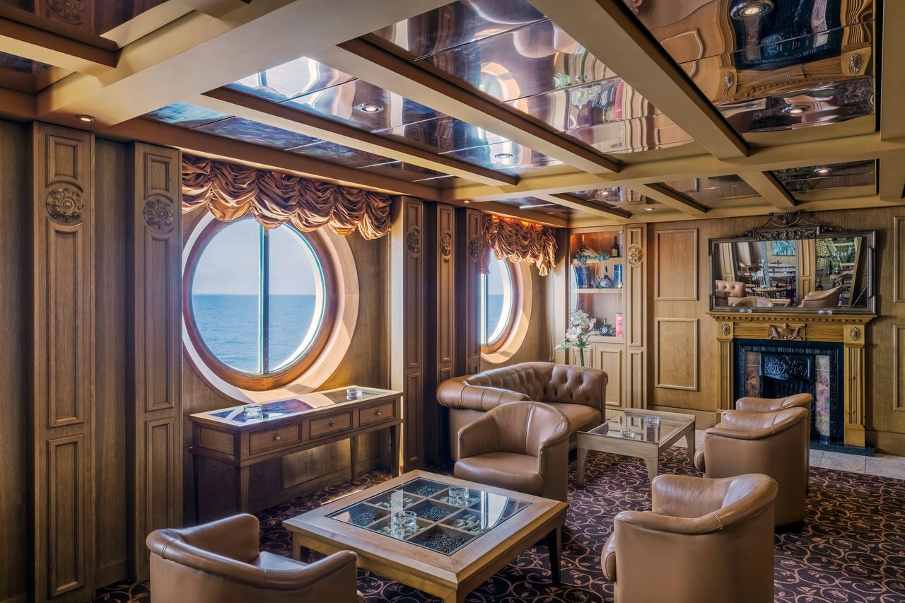 Ambassador Room on MSC Sinfonia features cozy seating and round windows overlooking the sea | MSC Cruises