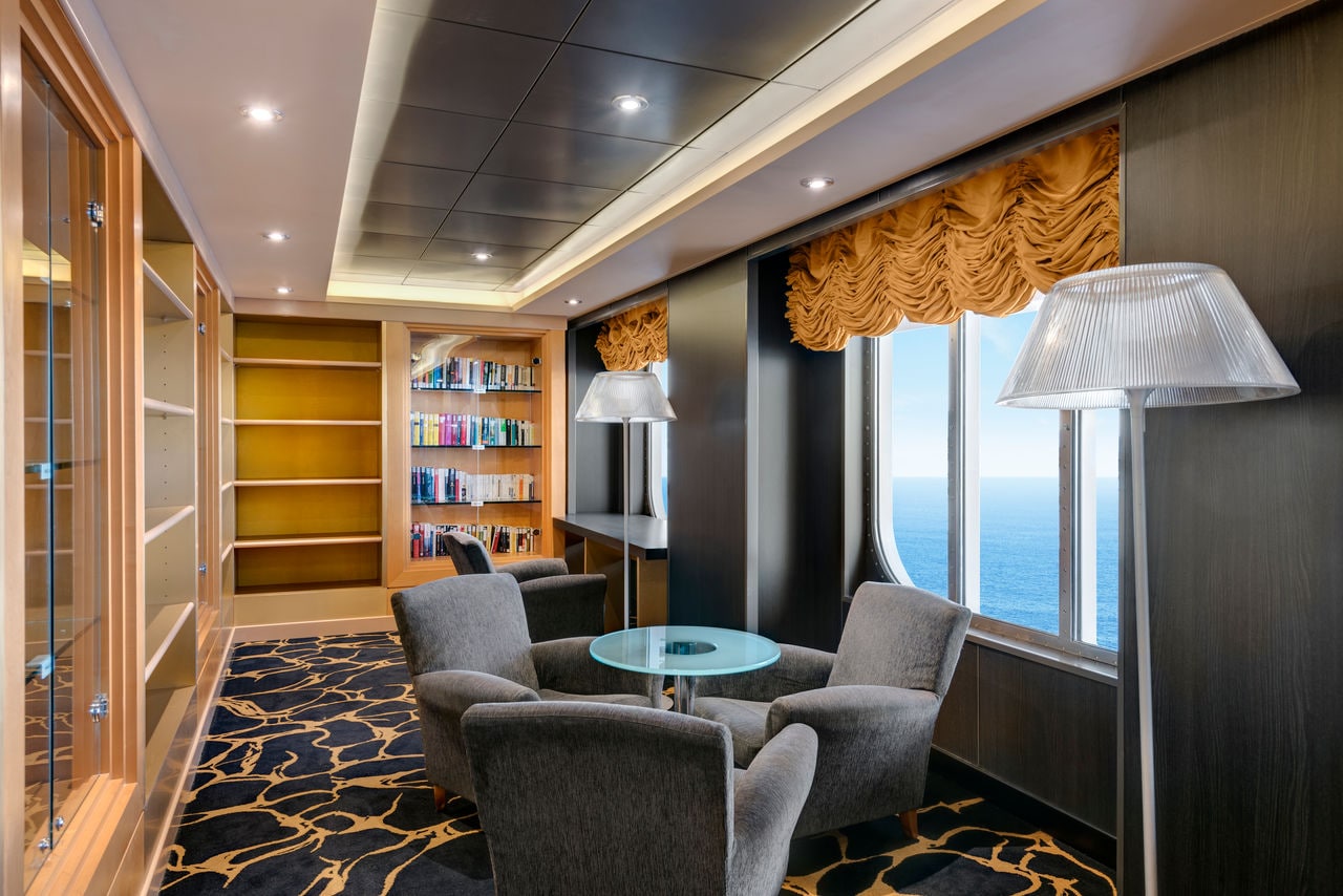 Modern lounge with comfortable armchairs and a table, large windows offering sea views | MSC Cruises