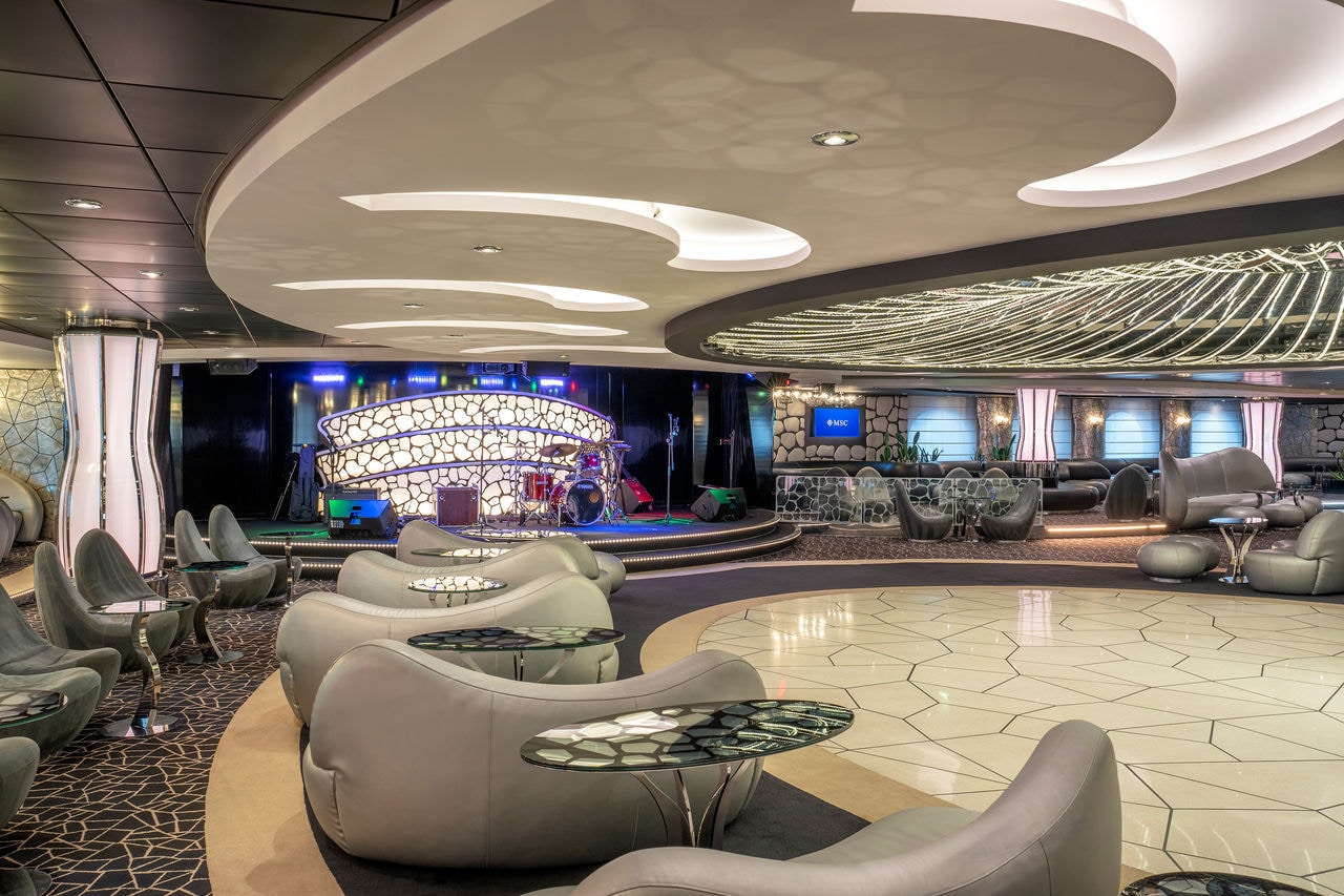 Modern lounge with stylish seating and a stage for music performances on MSC Divina | MSC Cruises