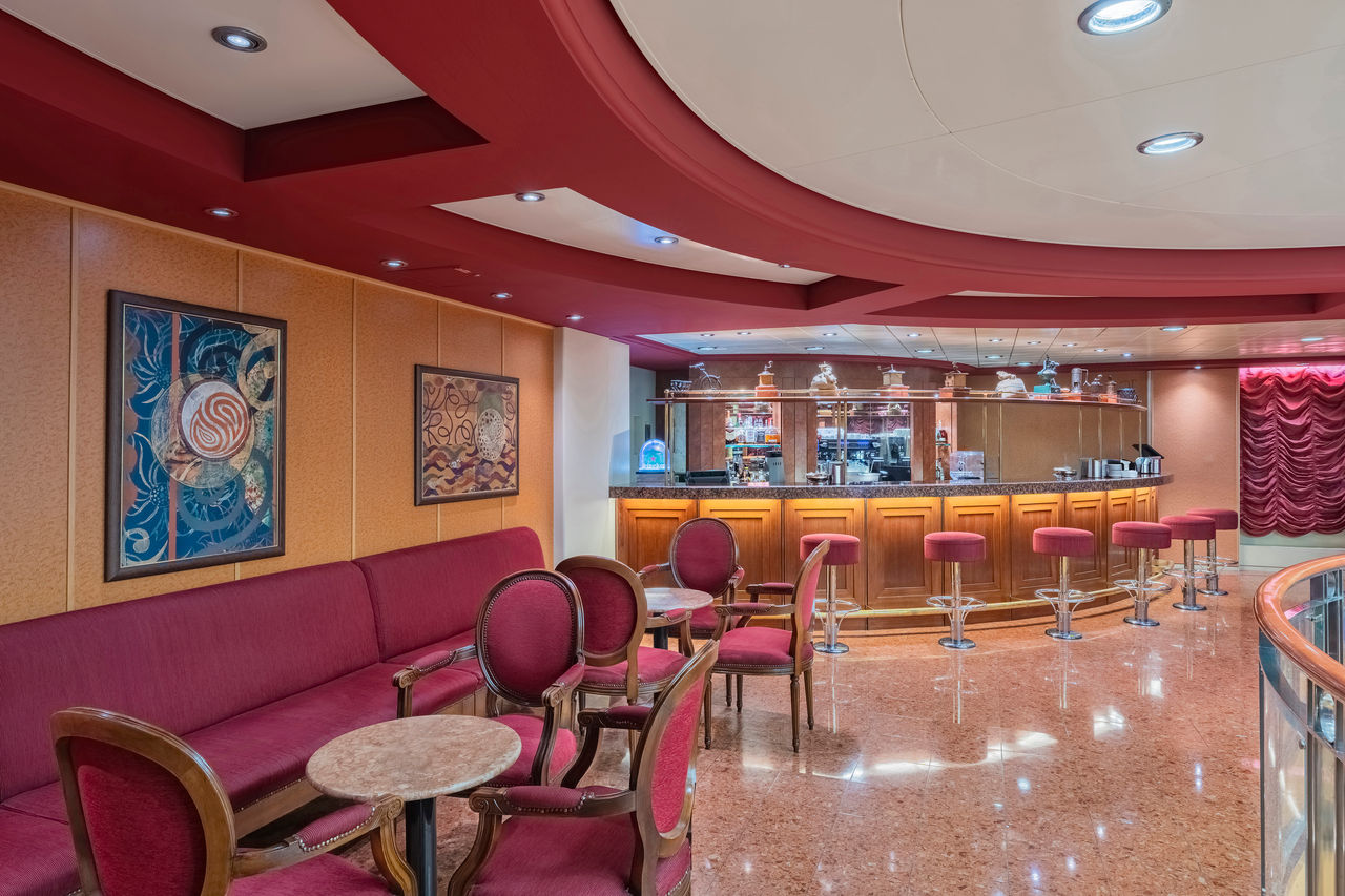 Spacious lounge featuring a bar counter, tables and comfortable seating for onboard relaxation | MSC Cruises