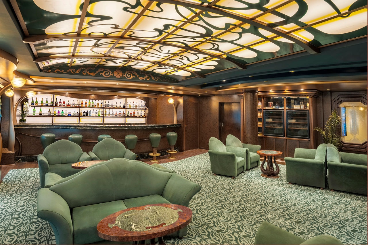 Elegant lounge with plush green seating and a refined bar area for relaxation | MSC Cruises