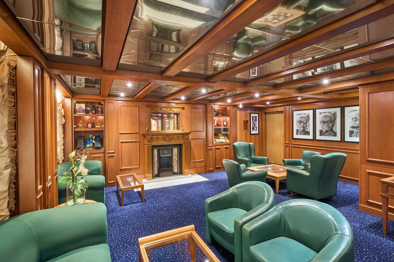 Spacious lounge featuring comfortable green armchairs and tables for relaxation onboard | MSC Cruises