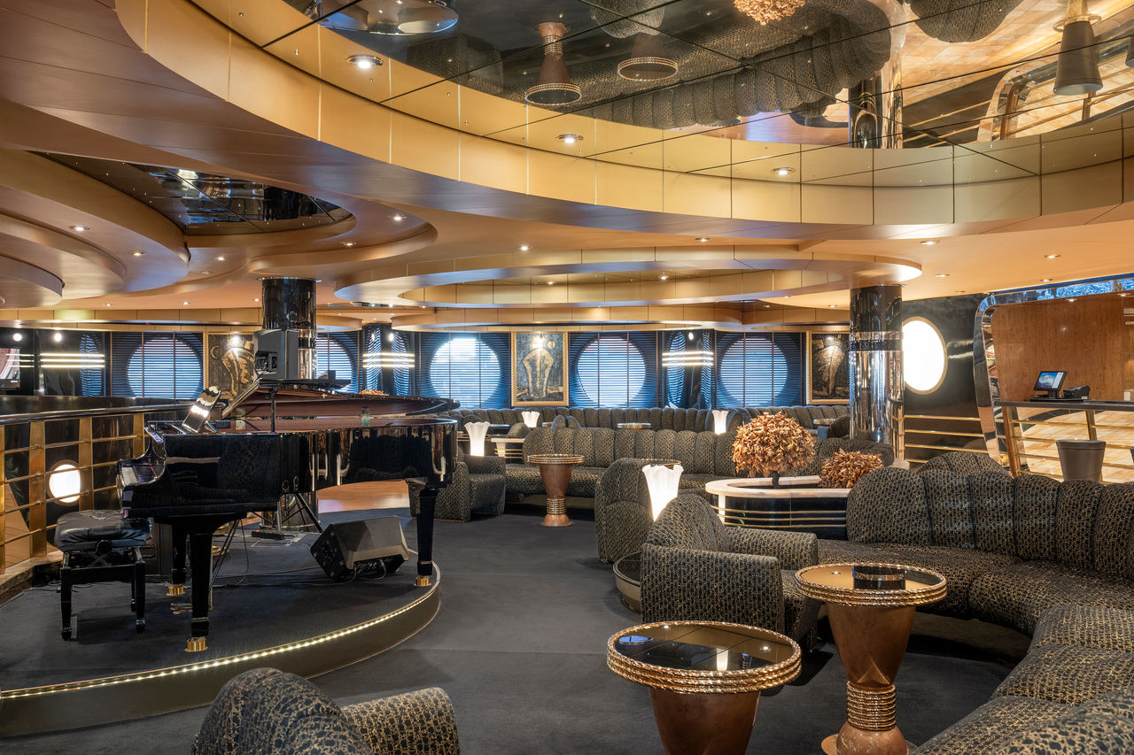 Spacious lounge with piano, bar counter and comfortable seating aboard MSC Preziosa | MSC Cruises