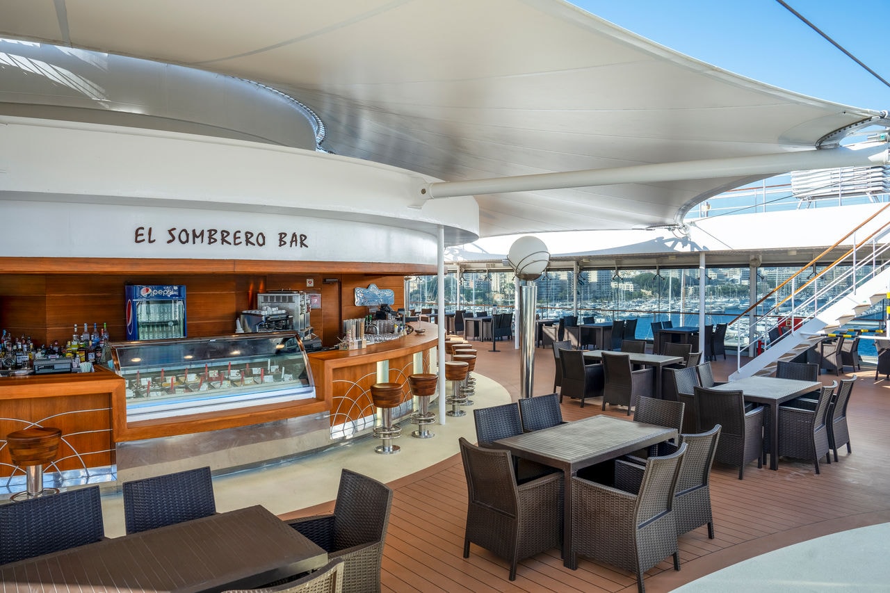 Outdoor seating at El Sombrero Bar on MSC Orchestra with a view of the sea and sky | MSC Cruises