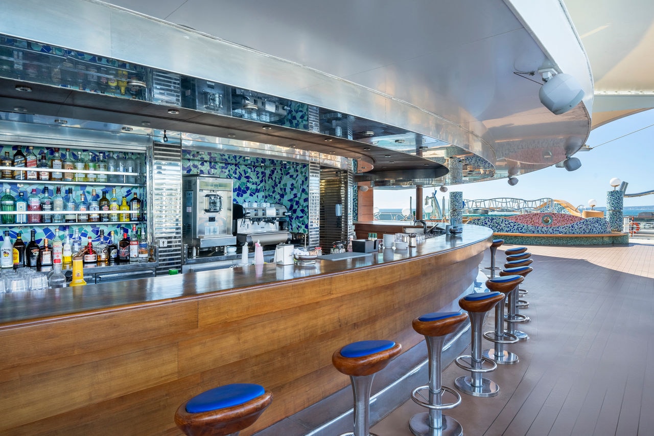 Outdoor bar with stylish stools and spacious seating area aboard MSC Fantasia | MSC Cruises