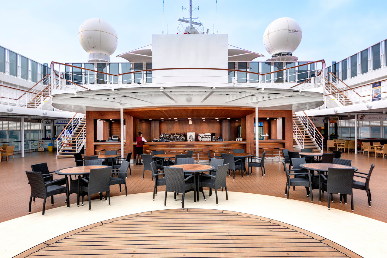 Outdoor bar with tables and chairs on the deck beneath an open sky | MSC Cruises