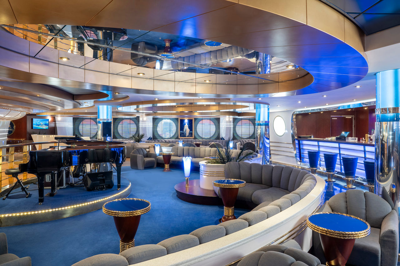 Spacious lounge with bar and piano on MSC Fantasia, comfortable seating areas | MSC Cruises