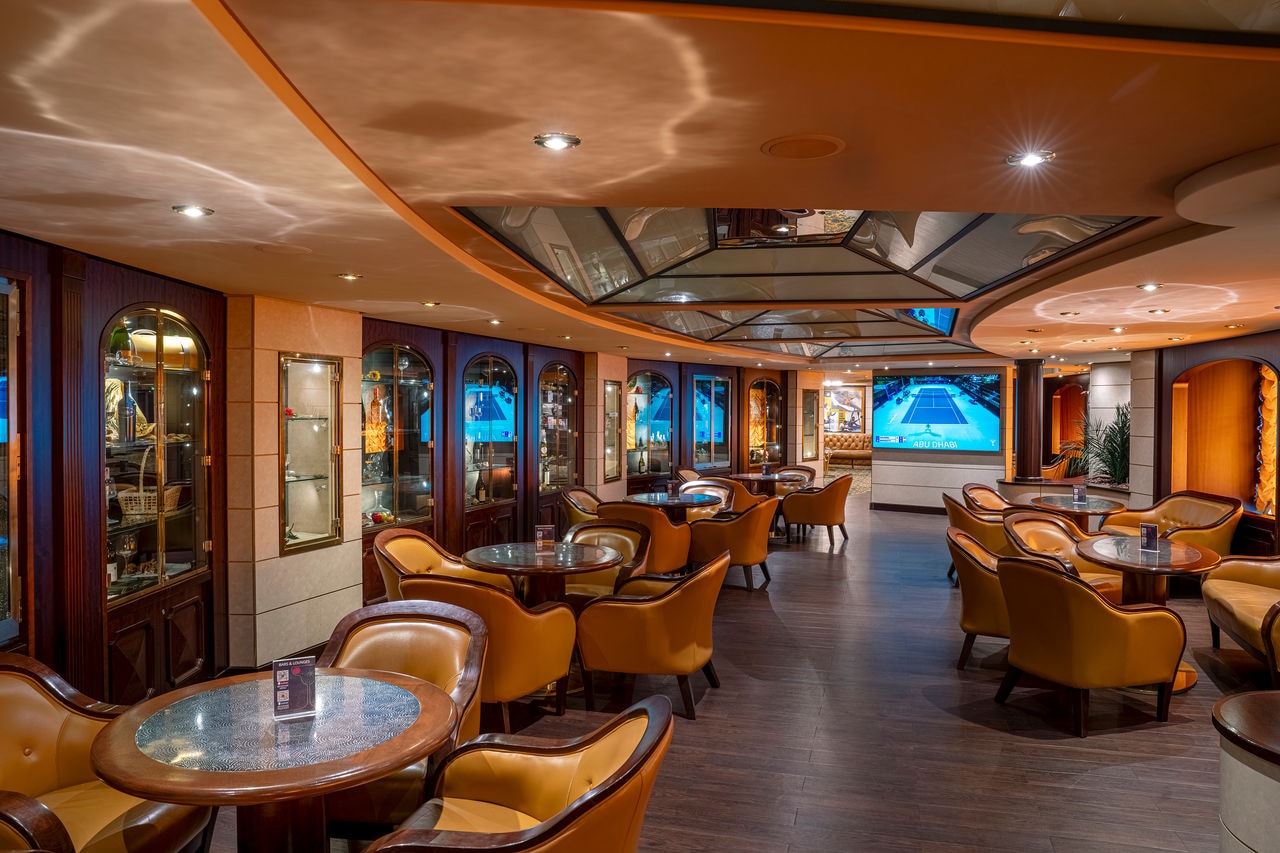 Spacious seating area with tables and armchairs in the lounge aboard MSC Orchestra | MSC Cruises