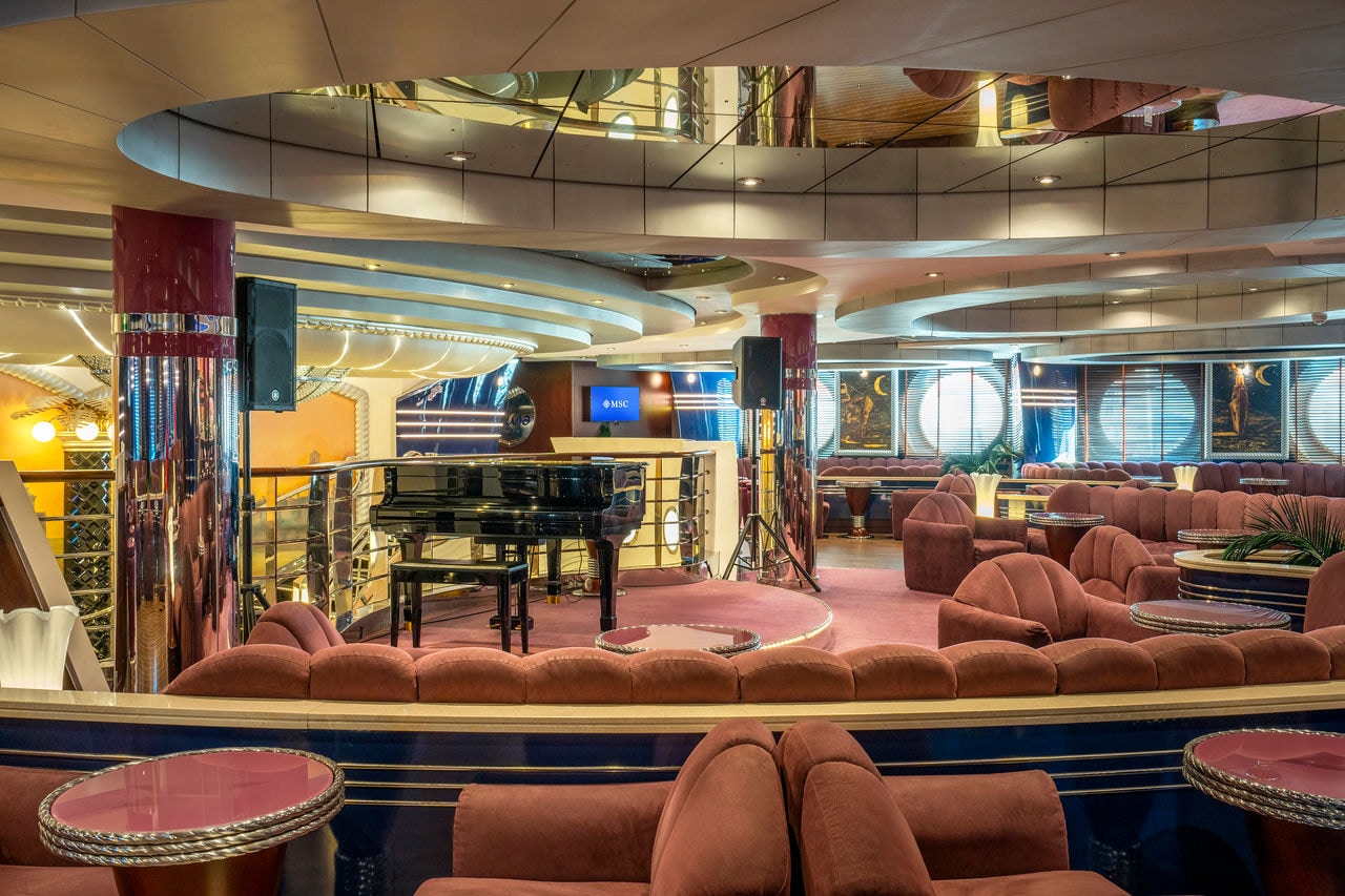 Spacious lounge featuring comfortable seating, a piano and elegant greenery | MSC Cruises
