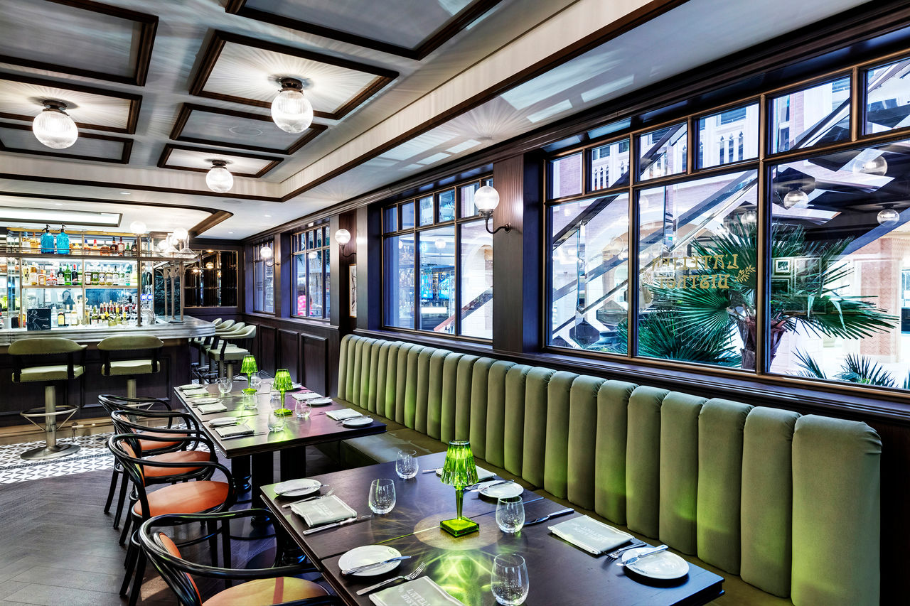L'Atelier Bistrot features tables and a green banquette beside large windows | MSC Cruises