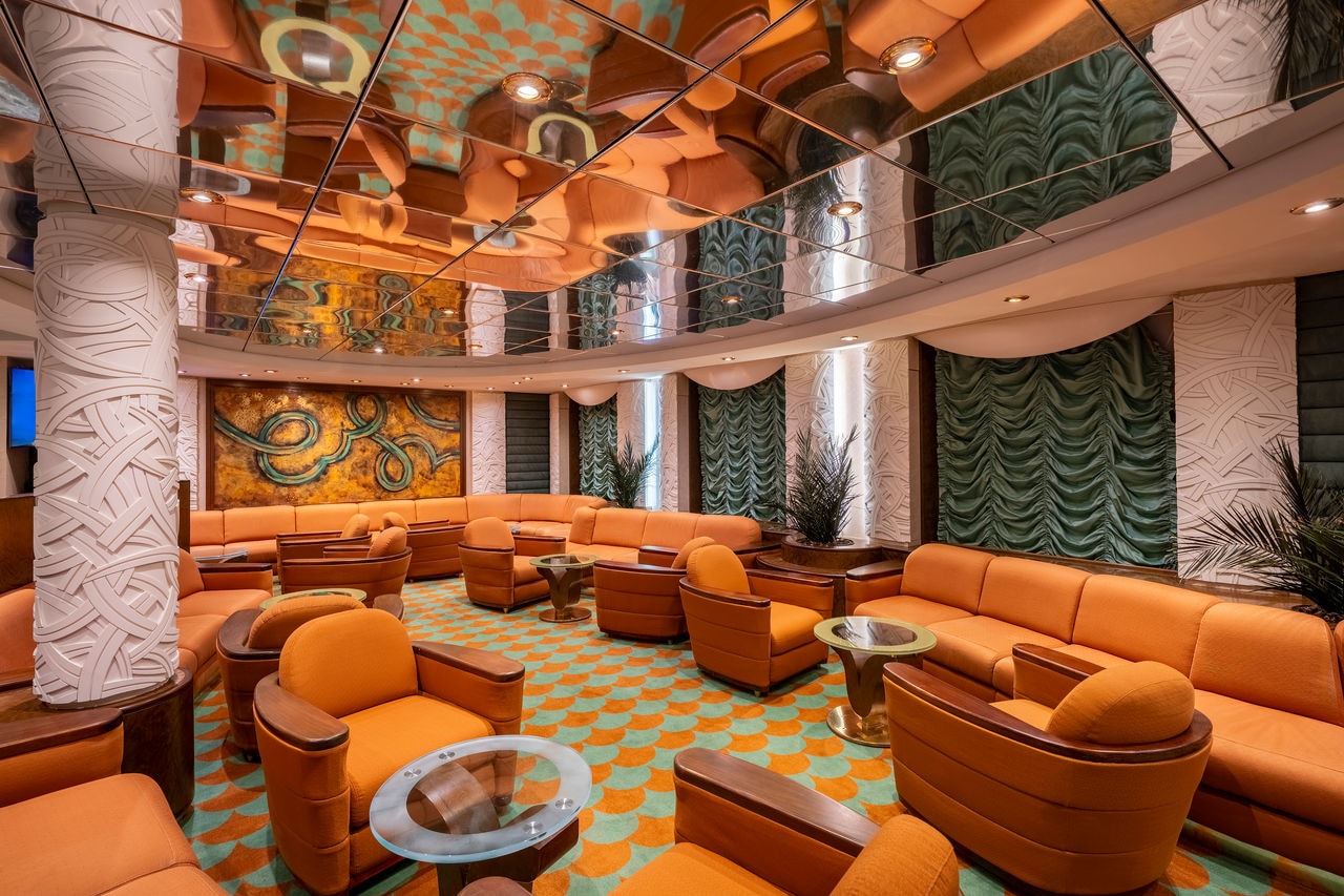 Spacious lounge with orange sofas and tables welcomes relaxing gatherings onboard | MSC Cruises