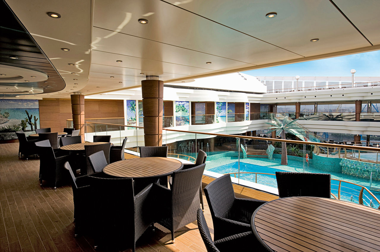 Inviting seating area with modern tables and chairs beside a covered pool | MSC Cruises