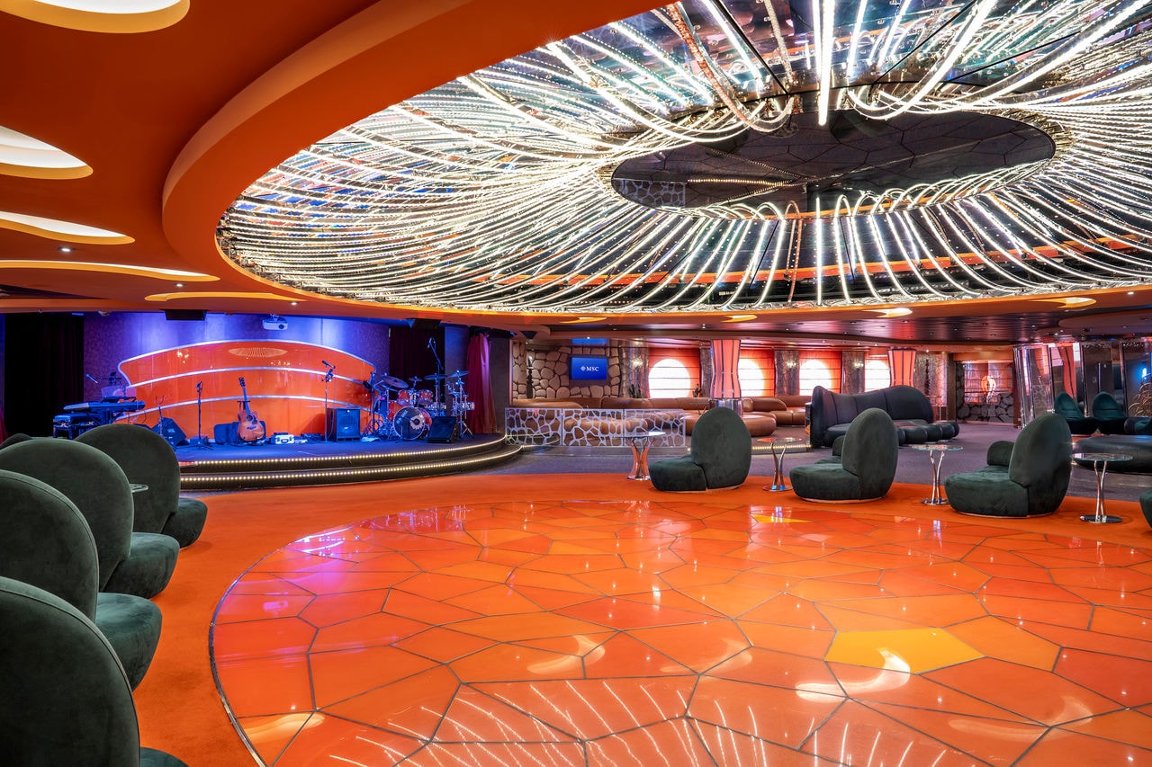 Spacious lounge with comfortable seating, stylish bar and stage for musical entertainment | MSC Cruises
