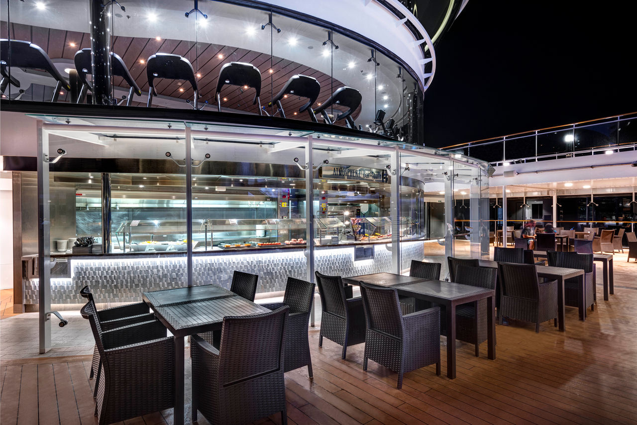 Bar and lounge on MSC Meraviglia with tables and chairs on the deck at night | MSC Cruises