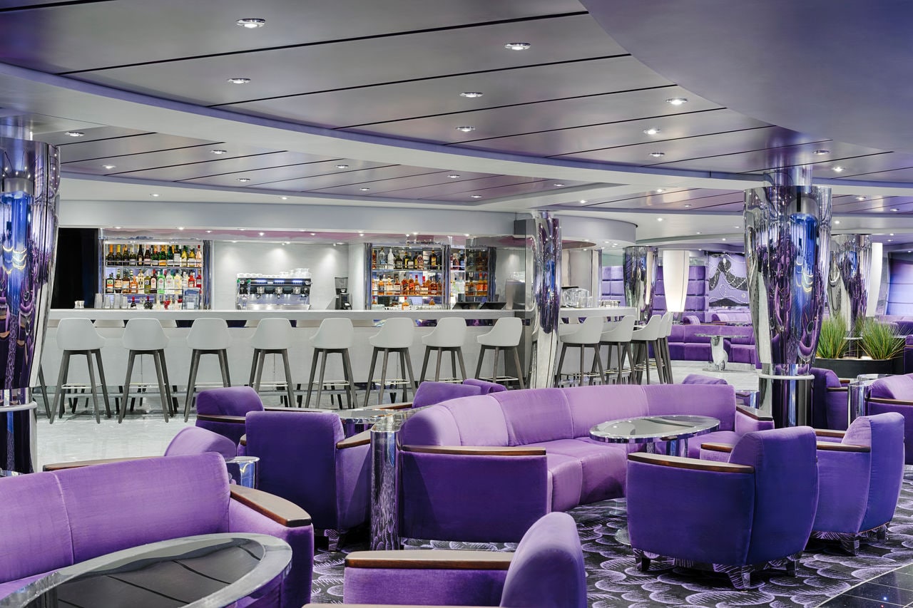 Contemporary lounge featuring purple sofas and a spacious bar for guests | MSC Cruises