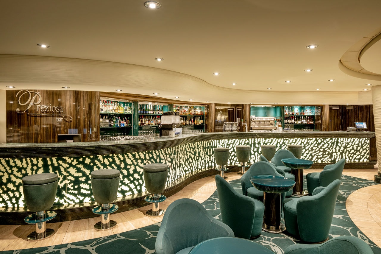 Spacious bar with armchairs and tables in the lounge area on MSC Preziosa | MSC Cruises