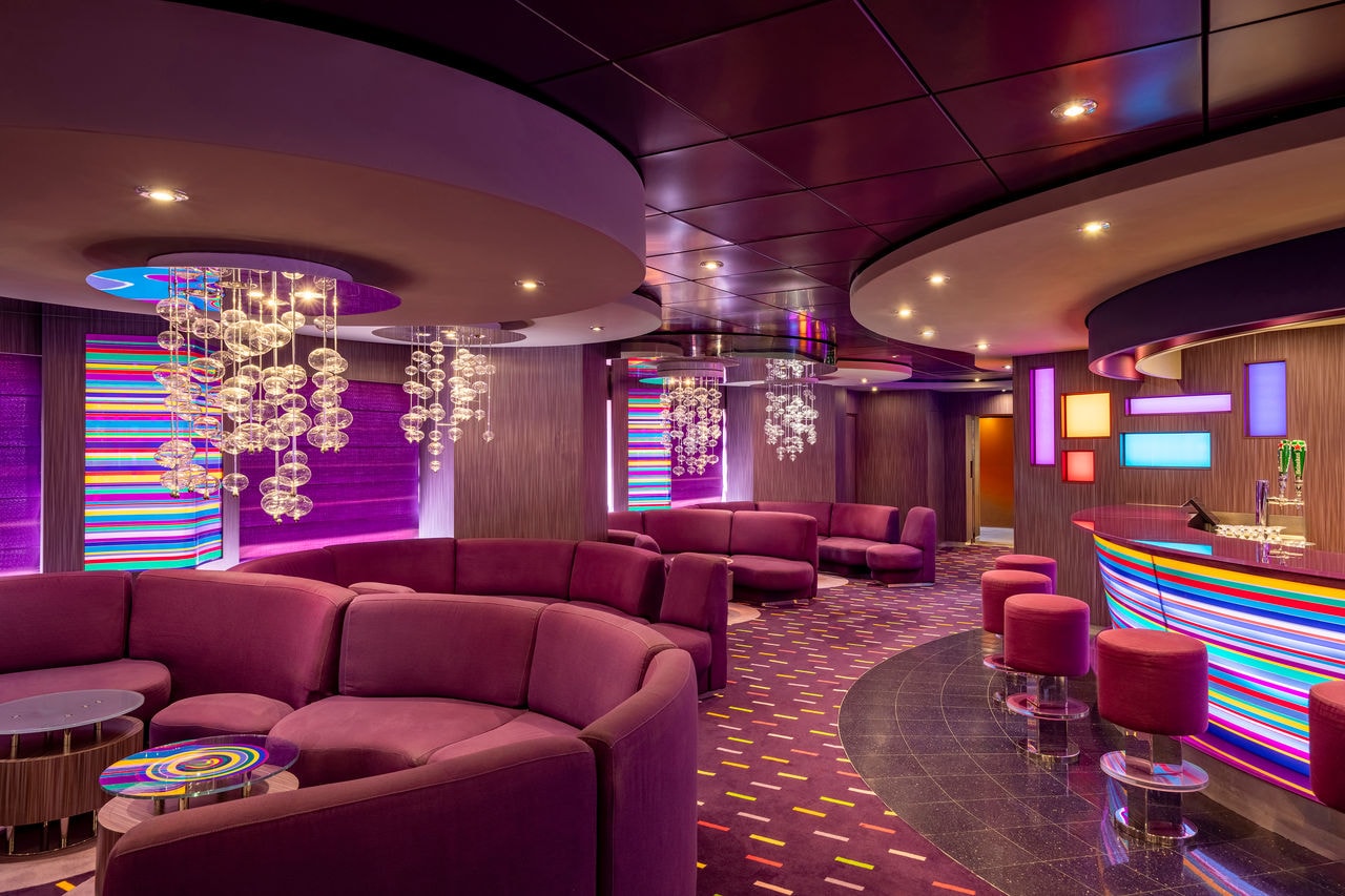 Inviting lounge with curved sofas, tables and chandeliers at The Purple Jazz Bar | MSC Cruises