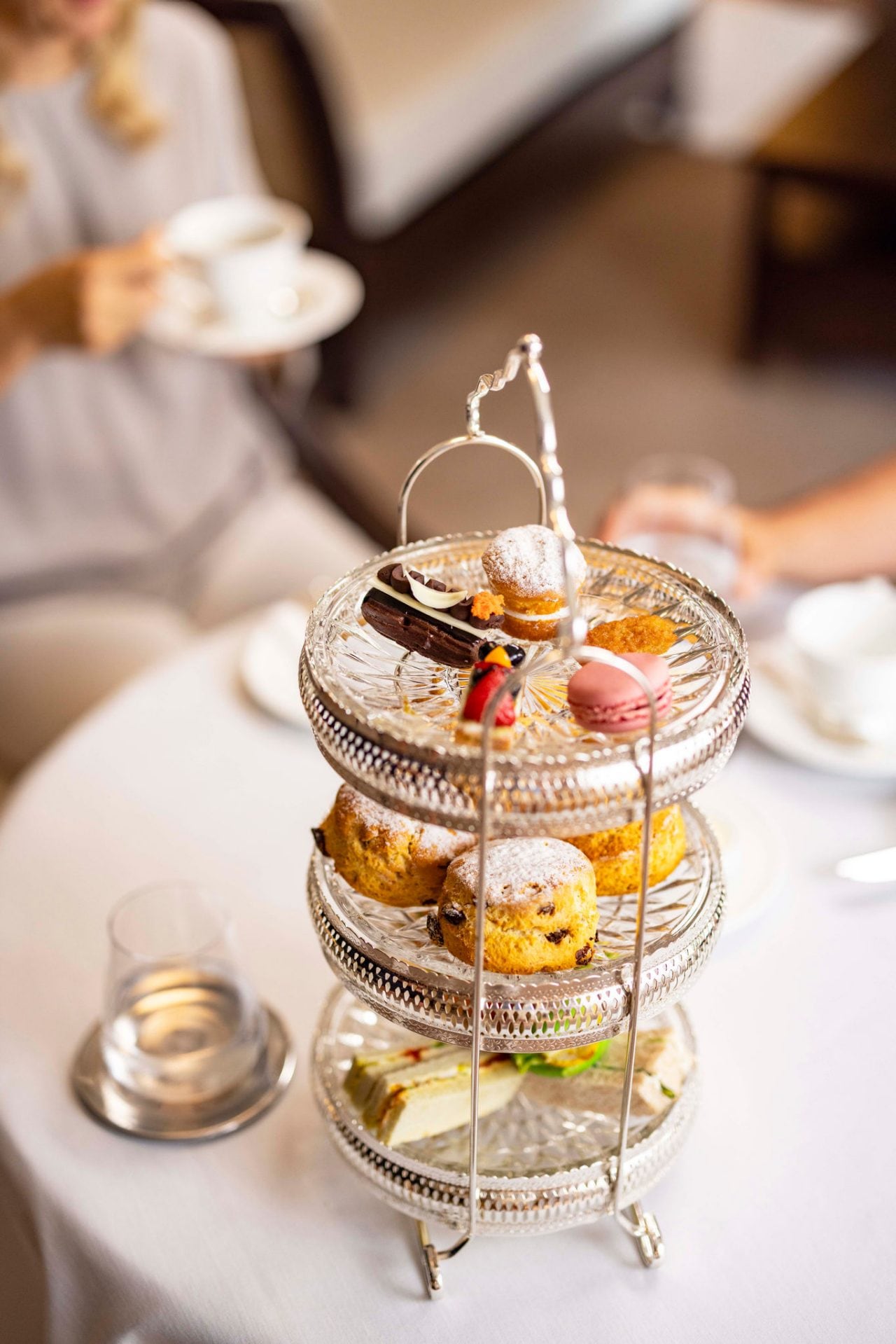 Two people share tea and assorted sweets on a tiered tray in a welcoming setting | MSC Cruises
