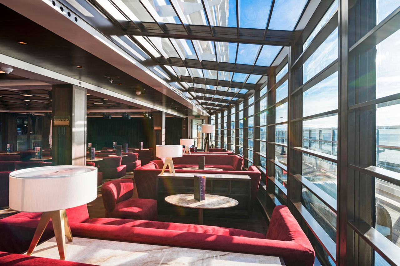Bright lounge with comfortable seating and large windows offering views of the sea | MSC Cruises