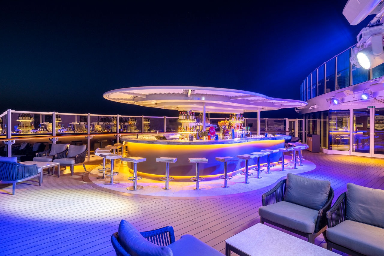 Sky Bar on MSC Seashore with outdoor seating, ambient lighting and a welcoming bar at night | MSC Cruises