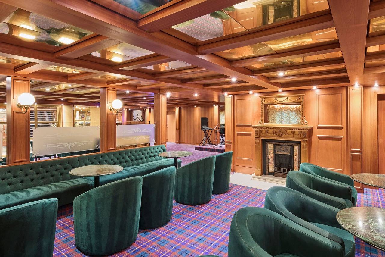 Spacious lounge with green armchairs and wooden accents inviting relaxation | MSC Cruises