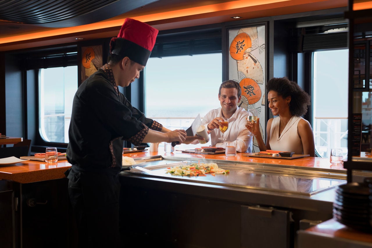 Chef prepares teppanyaki for a couple in Asian Market Kitchen on MSC Meraviglia | MSC Cruises