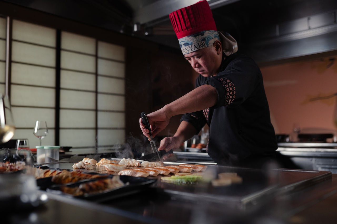 Chef prepares teppanyaki dishes on the grill in a welcoming restaurant setting | MSC Cruises