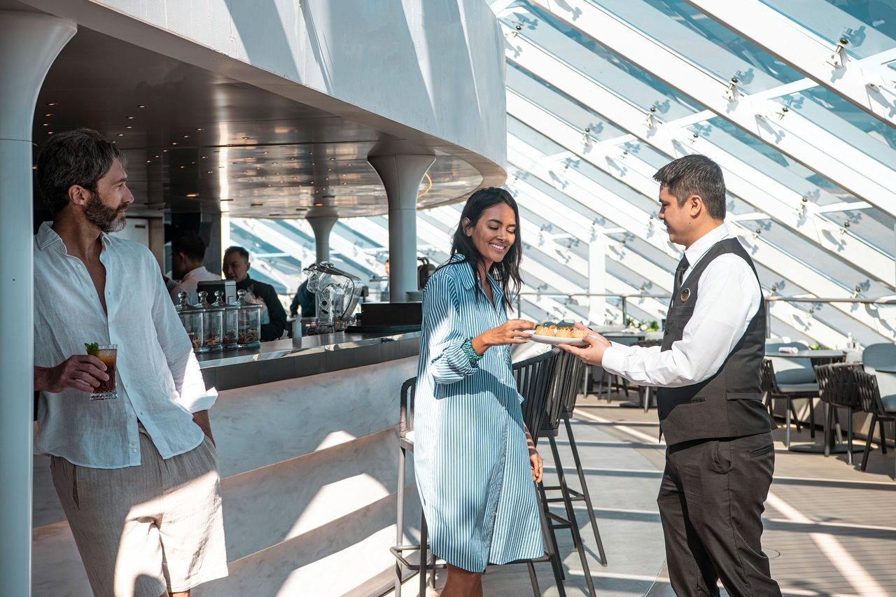 Guests enjoy drinks and food at the MSC Yacht Club bar on MSC World Europa | MSC Cruises