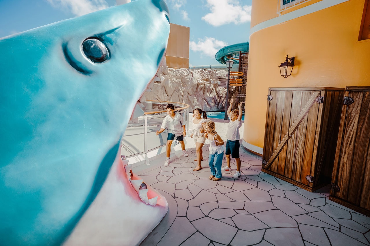 Large blue shark sculpture beside a lively children's activity area | MSC Cruises