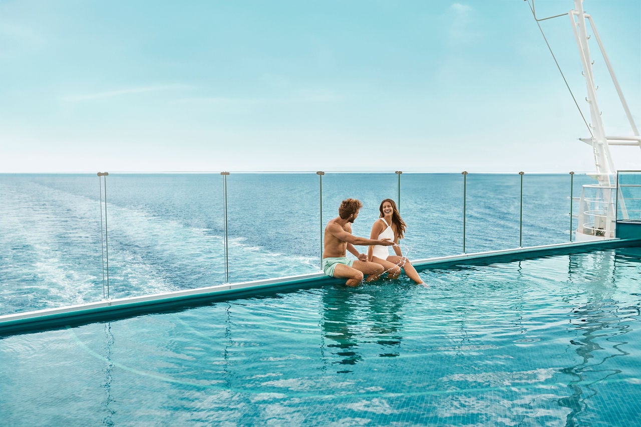 A couple enjoys the infinity pool overlooking the sea and sky on board | MSC Cruises