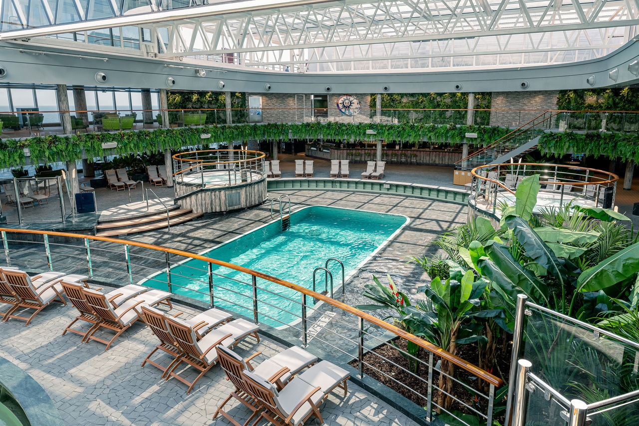 Pool area with loungers and lush greenery on board a modern cruise ship | MSC Cruises