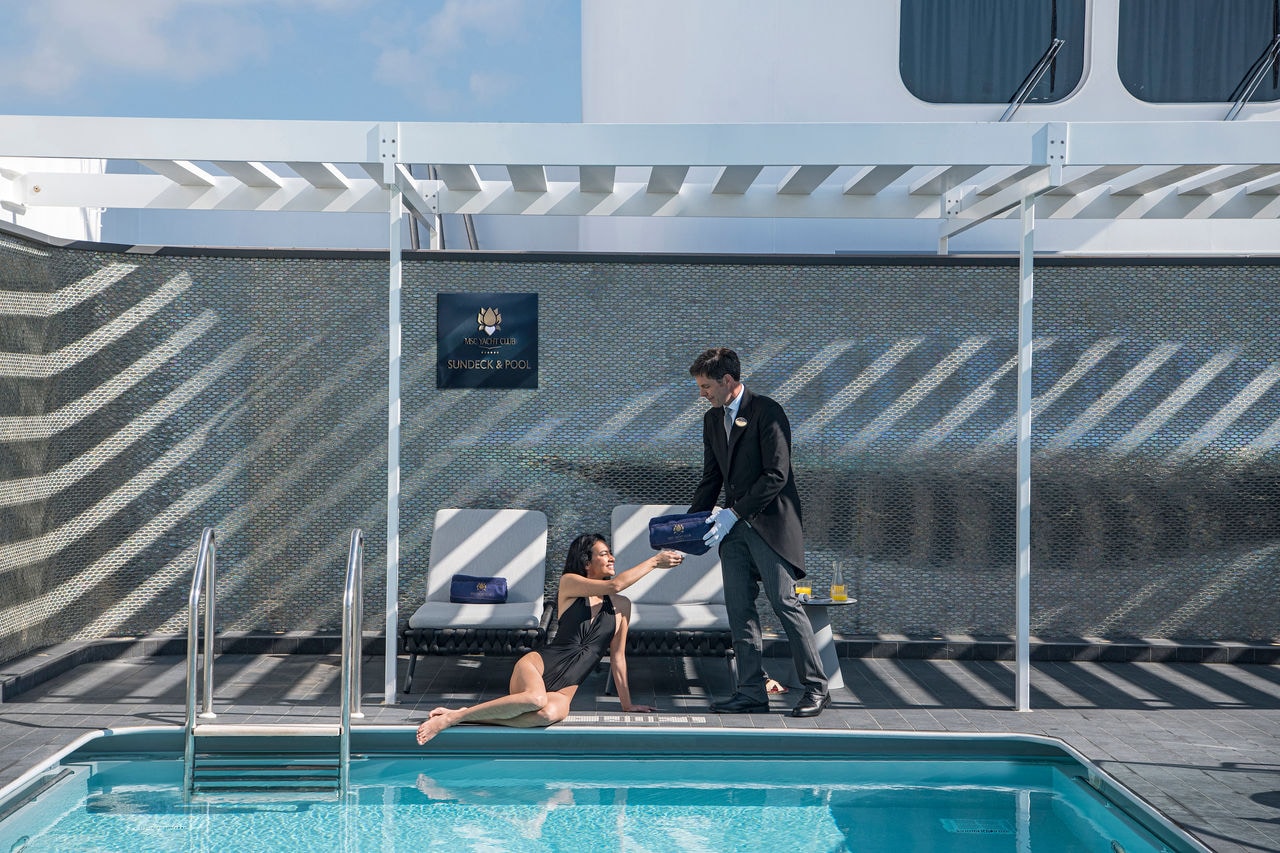 Guest relaxing on a sun lounger by the pool with butler service at MSC Yacht Club | MSC Cruises