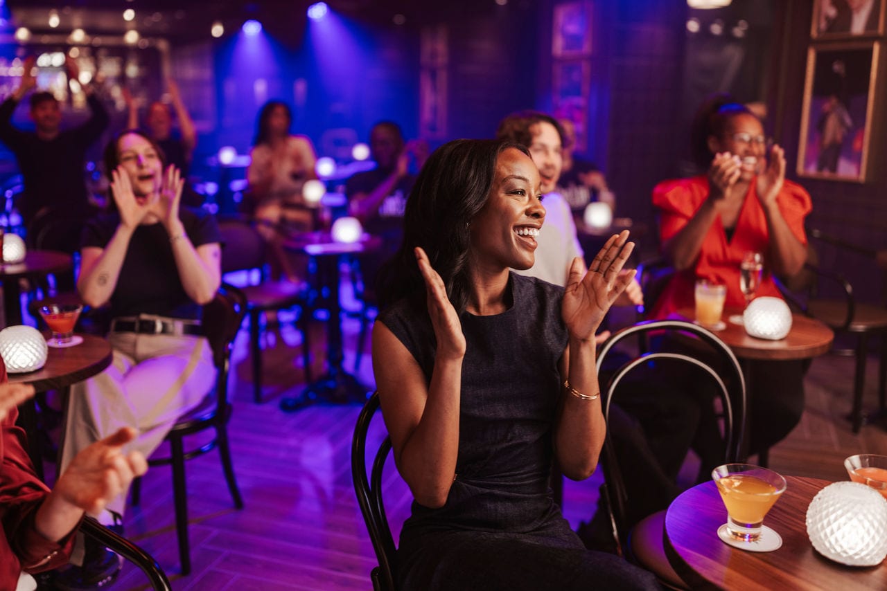 Guests clap and enjoy lively entertainment with cocktails in a vibrant lounge atmosphere | MSC Cruises