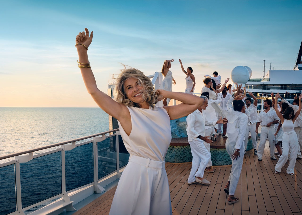 Woman dancing with friends on deck during a white party at sunset | MSC Cruises