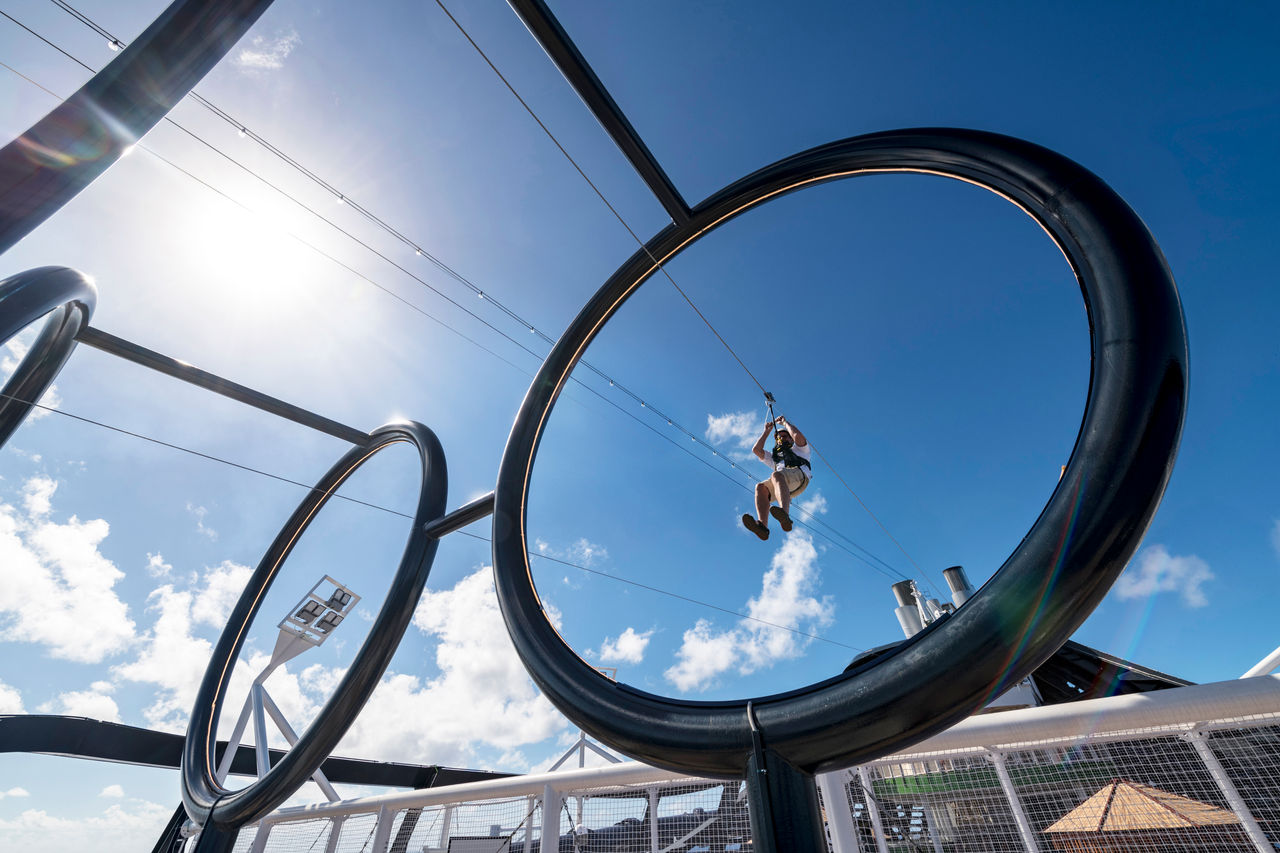 Exciting zip line experience on the deck of a cruise ship with circular structures and blue sky | MSC Cruises